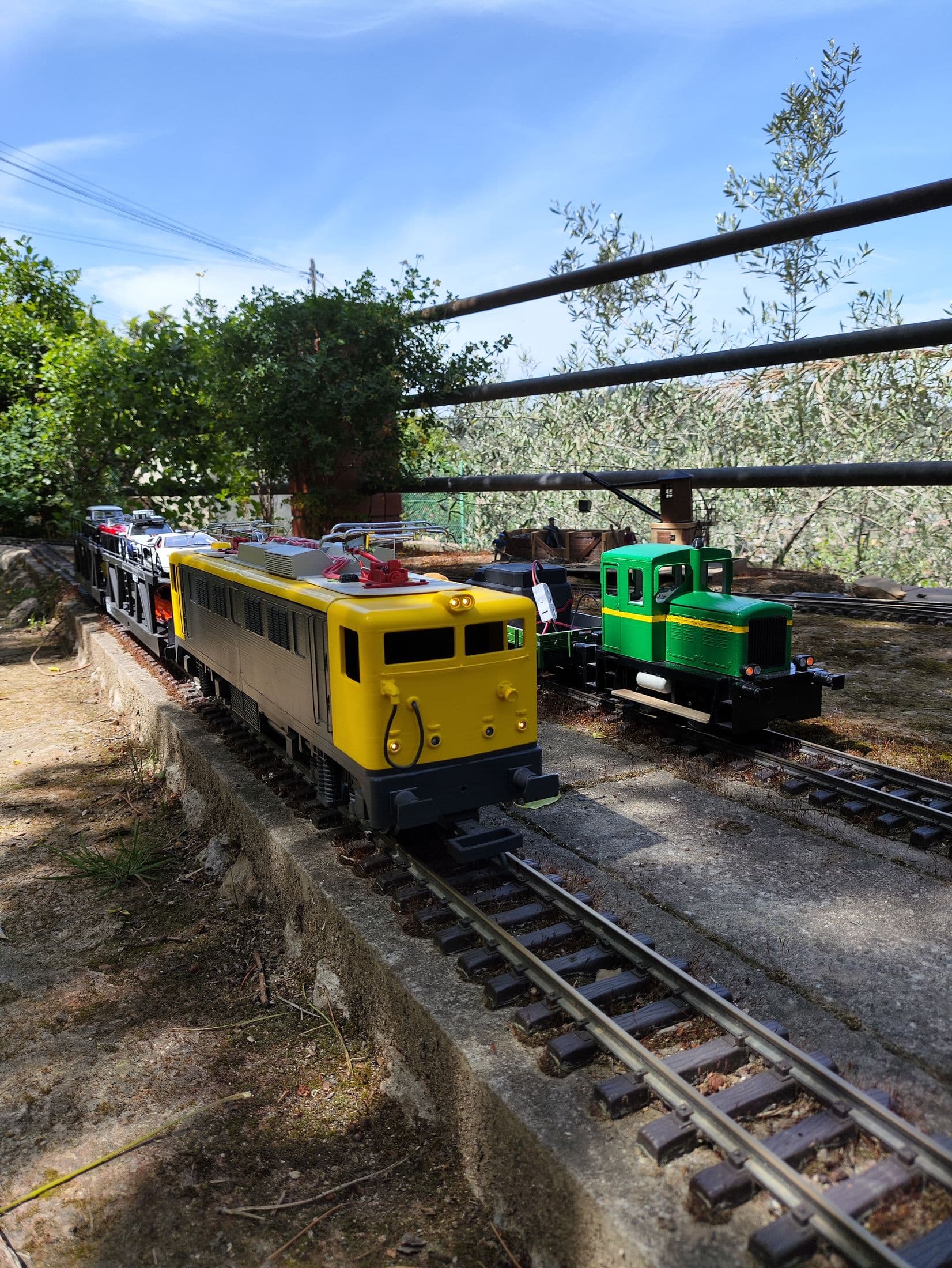 Locomotoras amarilla y verde bajo los olivos