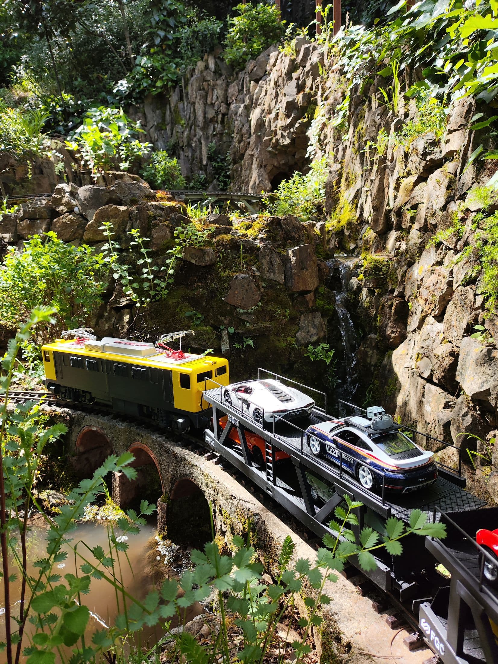 Tren TruRail cruzando un viaducto de piedra entre la vegetación